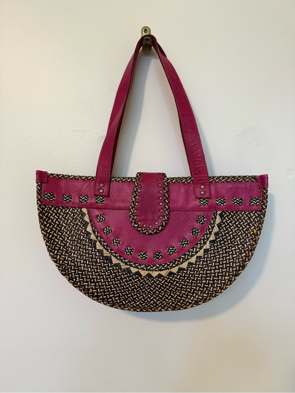 Unique woven straw bag with hot pink leather accents and metal details.